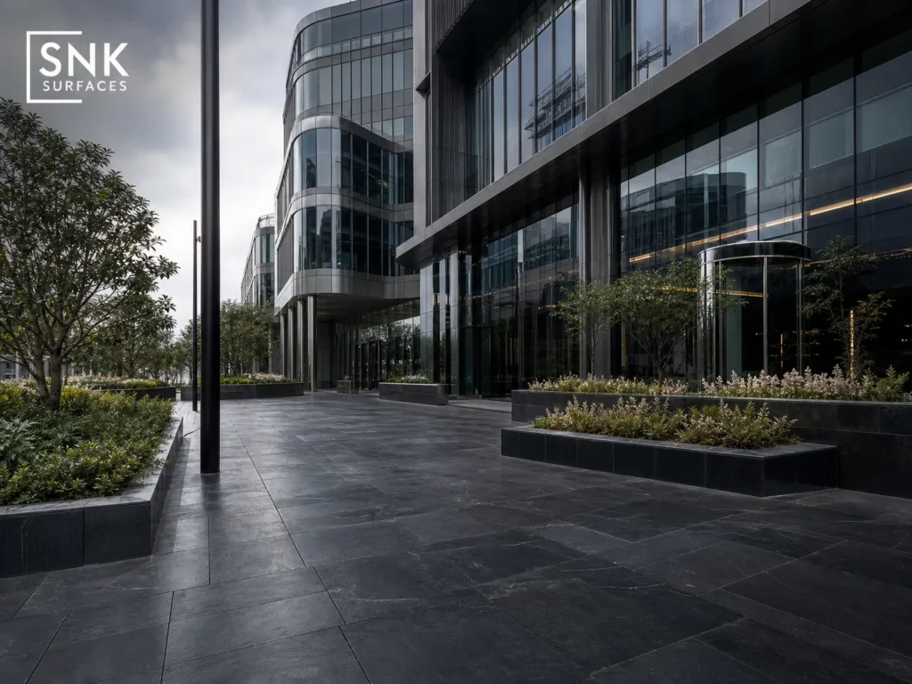 A modern UK commercial plaza showcasing premium dark paving solutions including black granite and charcoal porcelain.
