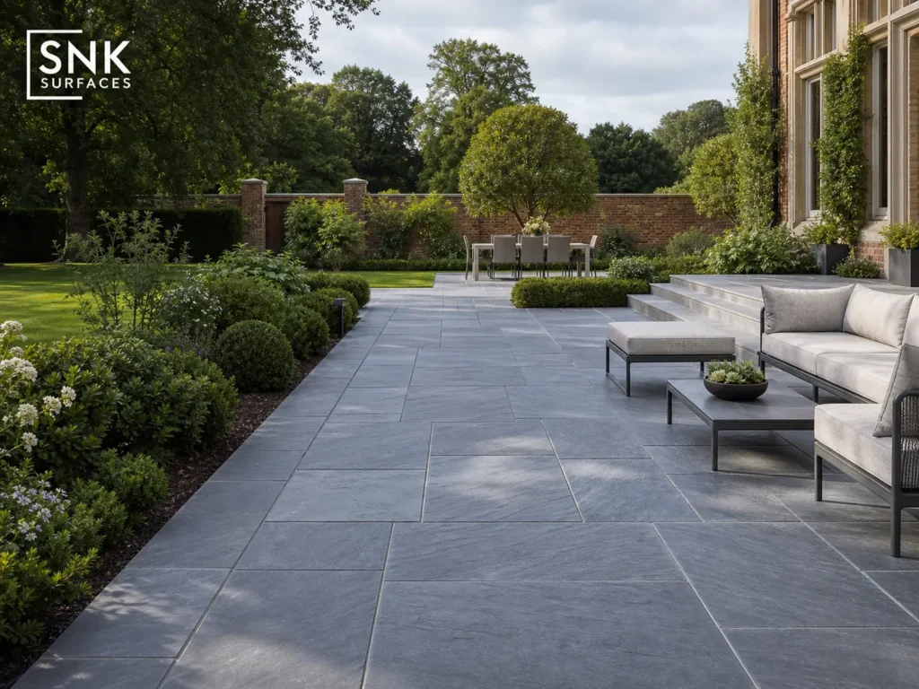 A luxury UK garden patio paved with natural Kota Blue Limestone slabs featuring a slate-blue and ash-grey riven texture.
